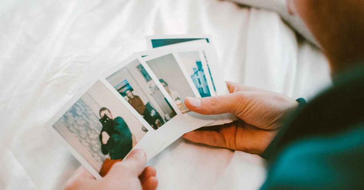 Hands holding a collection of vintage polaroid photos, capturing cherished memories in a cozy indoor setting.